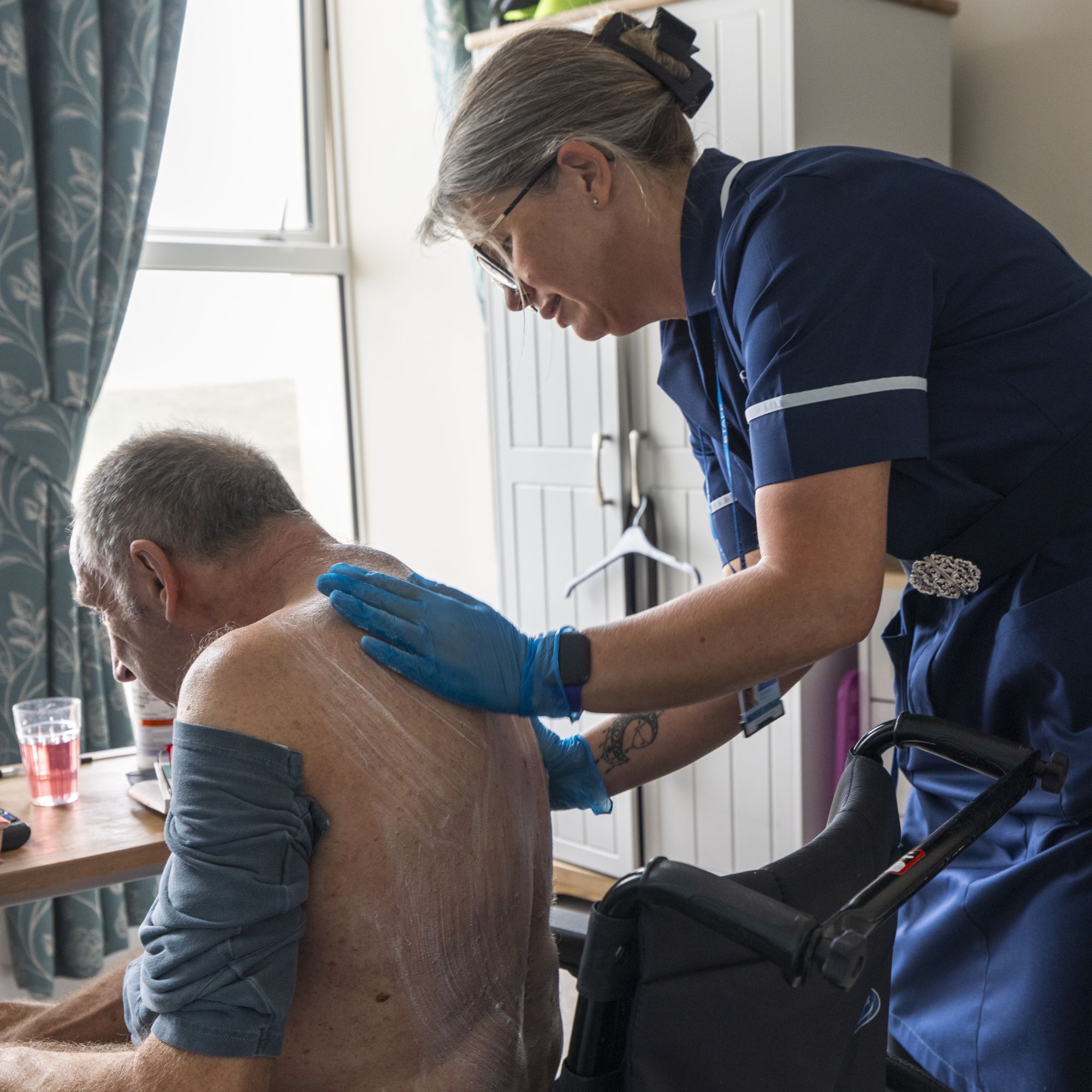 An elderly man receiving care from a female care professional