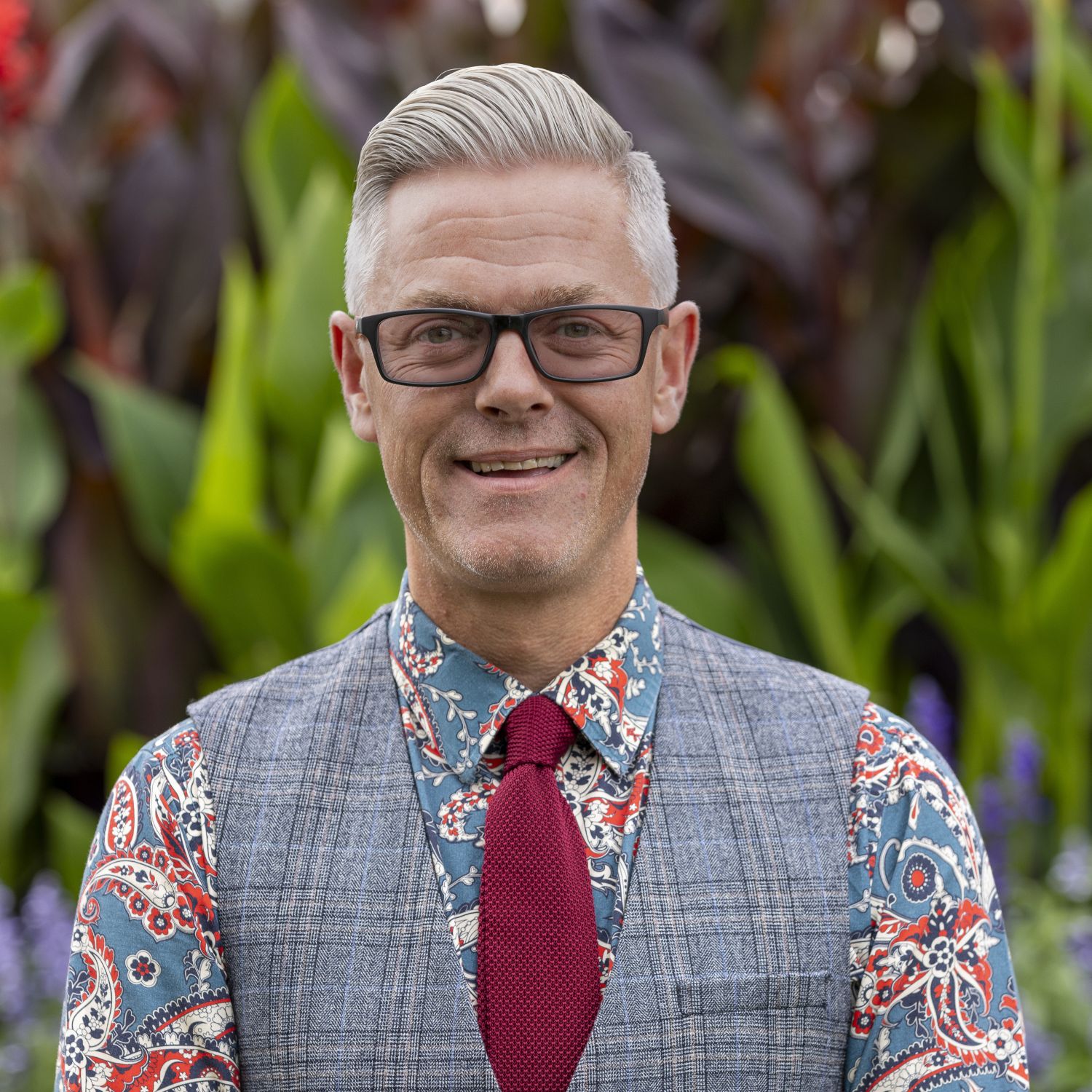 A man wearing glasses, shirt, waistcoat and a tie