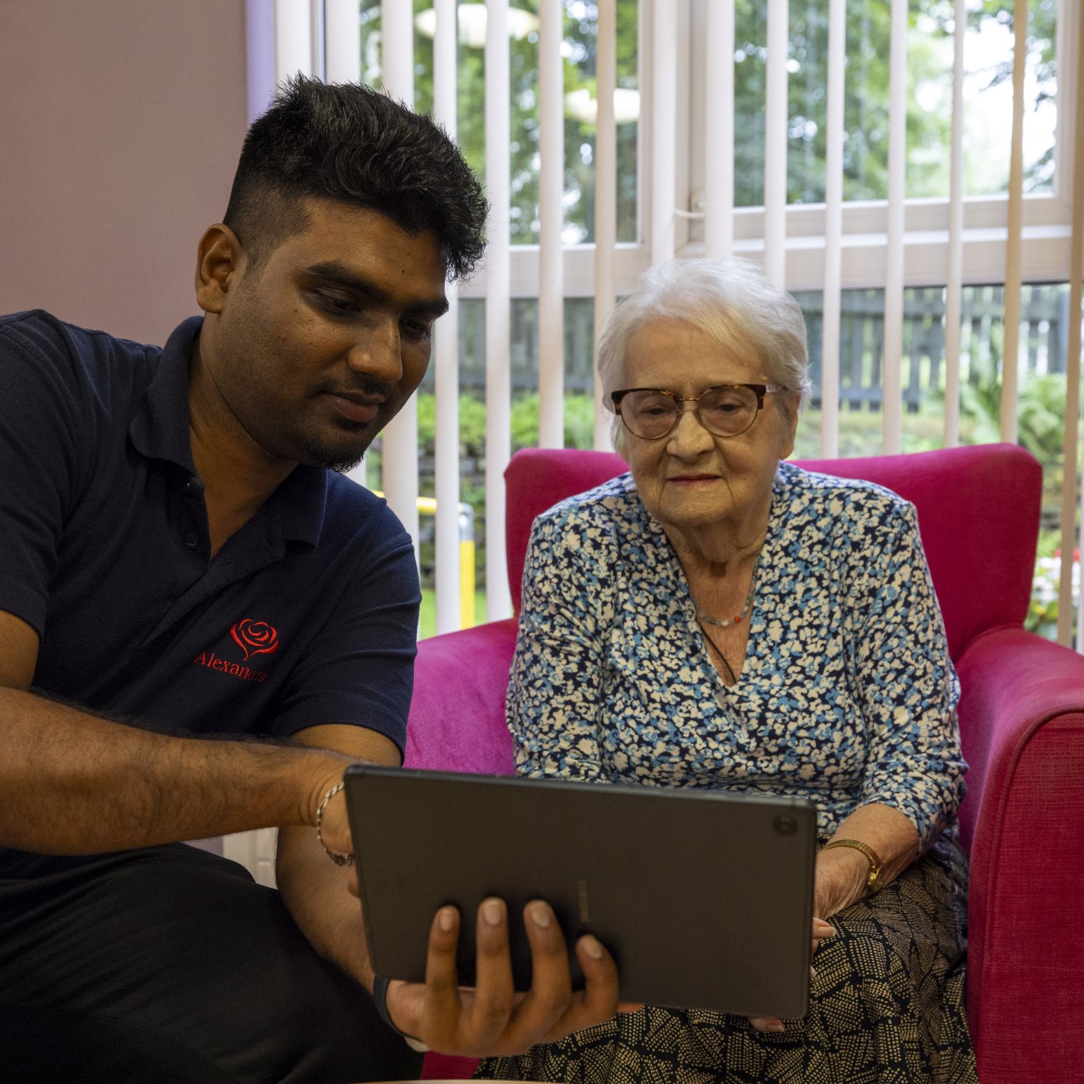 A young man showing an elderly woman something on a tablet device