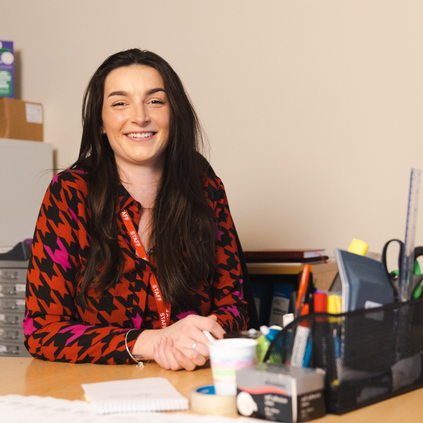 A young woman sitting at an office desk with lots of stationery