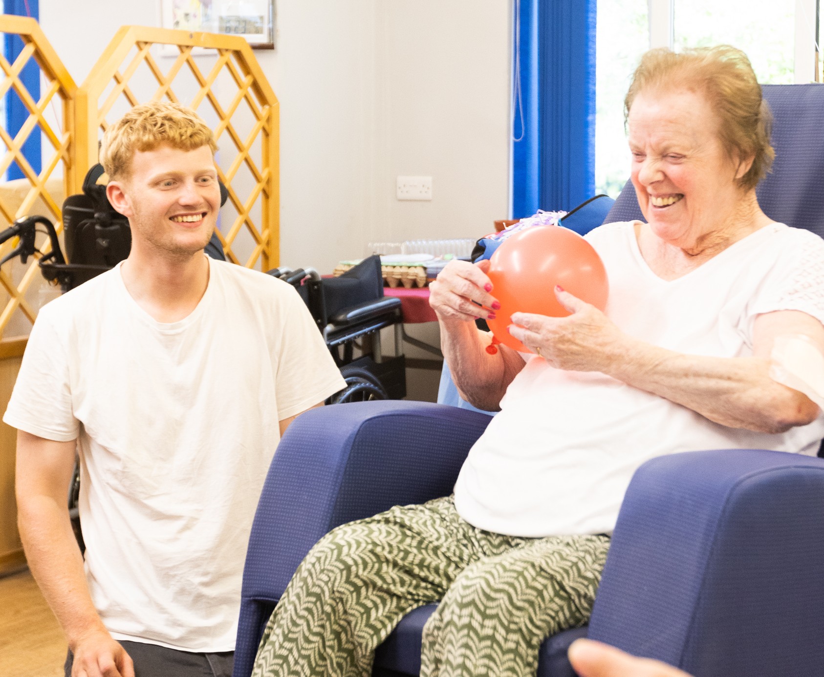 A male activity worker with a woman holding a balloon