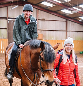 A man riding a horse with a woman standing alongside