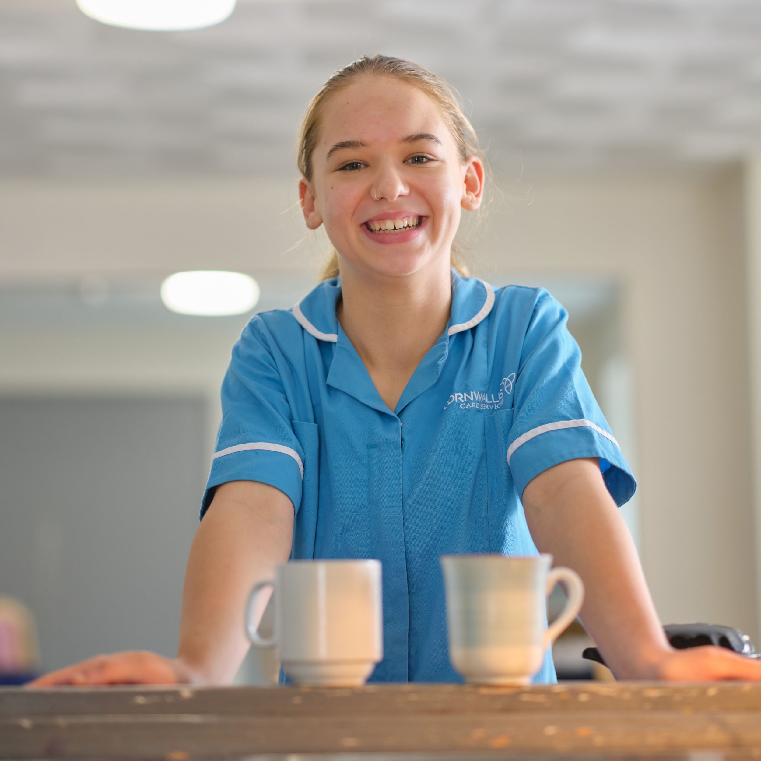 A carer at a table with two mugs