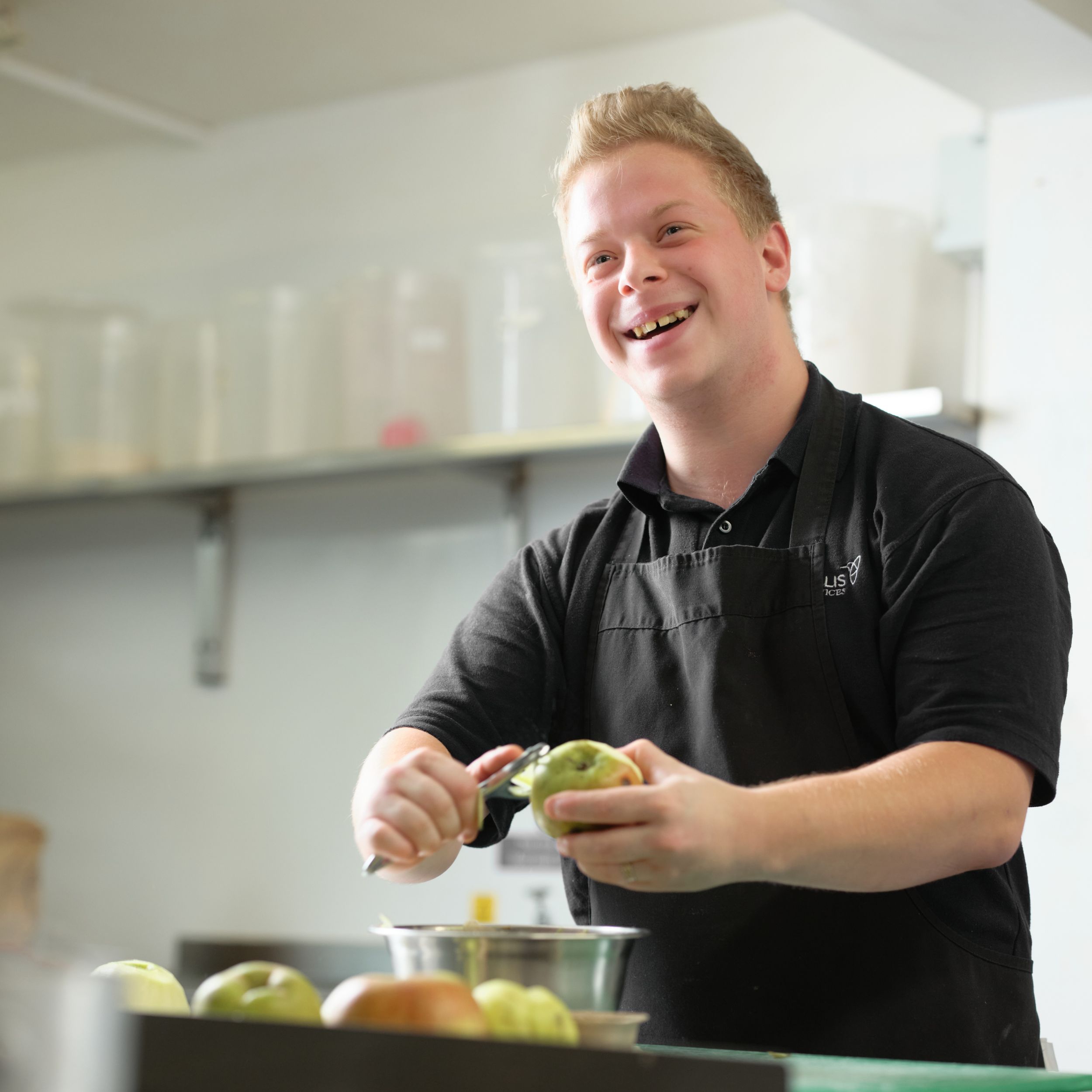 A young man peeling apples in a kitchen